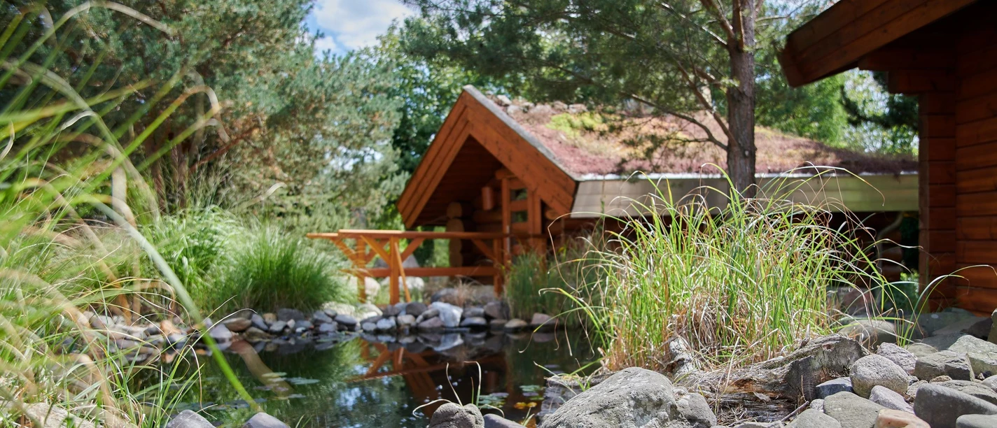 Saunadorf Oschatz - Wellness in der Leipzig Region Blick auf das Saunadorf mit kleinen Holzhütten an einem Bach in Oschatz gelegen