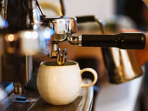 Une tasse de café est placée sous une machine à porte-filtre au Roots Pflanzencafé, gastronomie, café