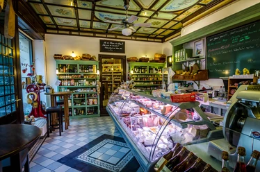 Salumeria Italiana - Gastronomie in Leipzig Das Salumeria von innen, mit Fokus auf der gefüllten Theke, dem Ambiente und Flair des Geschäftes sowie den dargebotenen Waren in den Verkaufsregalen im Hintergrund, feinkost, restaurant, genuss, kulinarik