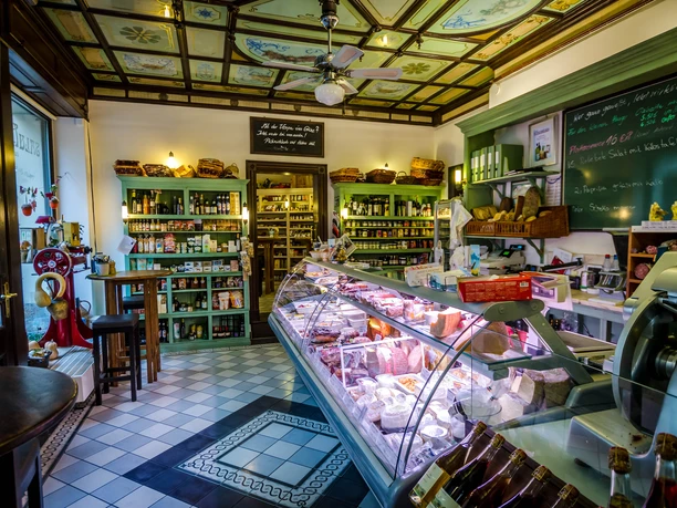 Le Salumeria vu de l'intérieur, avec un focus sur le comptoir rempli, l'ambiance et l'atmosphère du magasin ainsi que les marchandises présentées sur les étagères de vente au fond, épicerie fine, restaurant, plaisir, culinaire