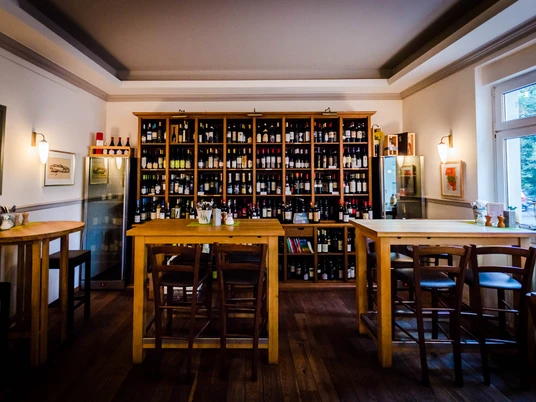 Salumeria Italiana - Gastronomie in Leipzig Blick in das Feinkostgeschäft mit Bistro; Sitzbereich, Holzregale mit Weinvielfalt und herrliche Beleuchtung, restaurant, gastronomie