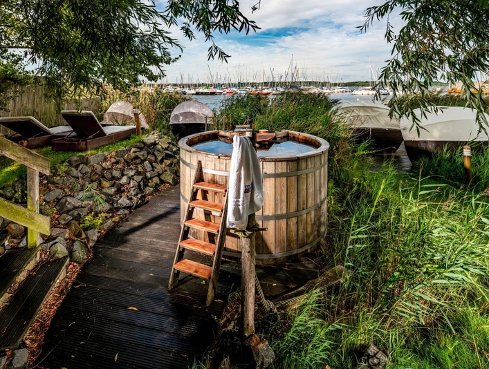Badezuber Sauna im See - Wellness in Leipzig und Region Ein Badezuber und Liegen zum Entspannen stehen in dem Außenbereich der Wellness-Einrichtung Sauna im See.