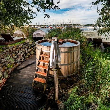 Ve venkovní části wellness centra Sauna im See je k dispozici vířivka a lehátka pro relaxaci.