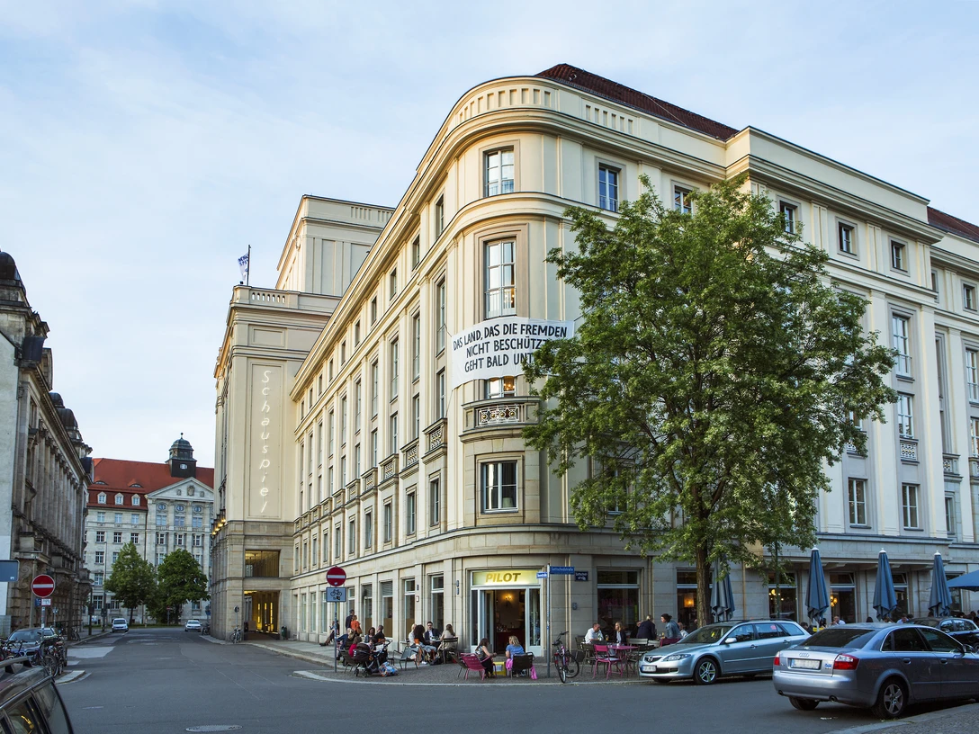 Schauspielhaus Leipzig - Bühnen in Leipzig Das Schauspielhaus bei sonnigem Wetter, mit Gästen, welche vor und im Café im Erdgeschoss verweilen