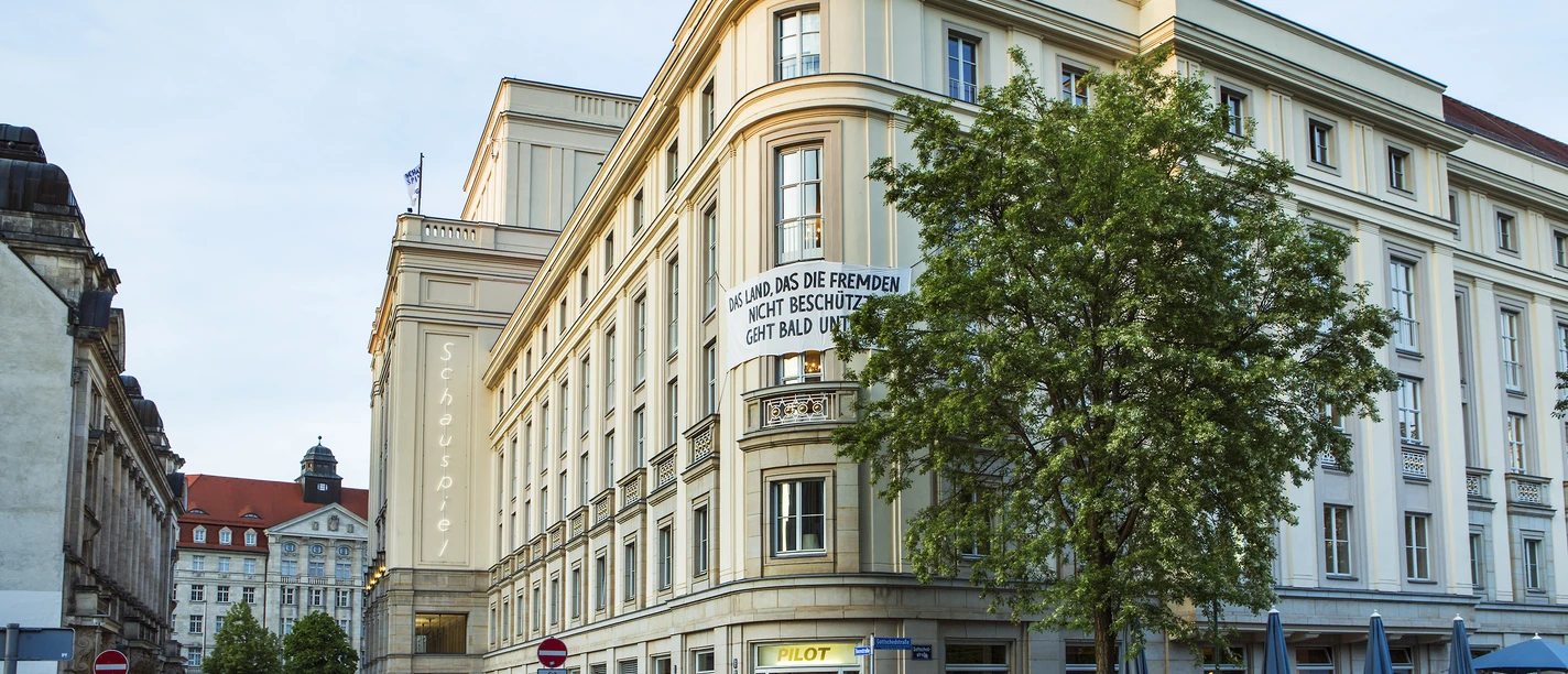 Schauspielhaus Leipzig - Bühnen in Leipzig Das Schauspielhaus bei sonnigem Wetter, mit Gästen, welche vor und im Café im Erdgeschoss verweilen