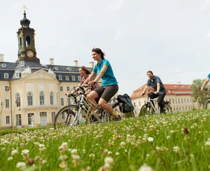 Grupa rowerzystów jedzie przed zamkiem Hubertusburg w Wermsdorfie