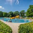 Schreberbad Leipzig - Freizeiterlebnisse in der Leipzig Region Blick auf das Hauptschwimmbecken im Schreberbad, mit gelber Rutsche und vielen Badegästen an einem Sommertag, Freizeitaktivität, Badespaß