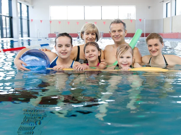 Une famille avec des enfants en gros plan dans la piscine du Sportbad Markkleeberg, les enfants ont des bouées et un ballon de plage pour jouer, excursion, loisirs