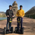 Stadtstromer Segwaytour - Erlebnisanbieter in Leipzig Blick auf das Völkerschlachtdenkmal Leipzig im Hintergrund und zwei Männer auf Segways die eine Stadtführung des Erlebnisanbieters Stadtstromer besuchen