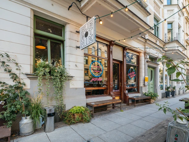 Subbotnik - Kneipen & Bars in Leipzig Fotografie des Außenbereiches des Subbotniks sowie der angrenzenden Gebäude, der Deko und Pflanzen vor dem Lokal sowie der Schaufenster, kneipe, bar, nachtleben