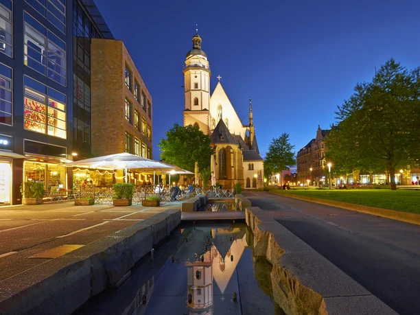 Thomaskirche Leipzig - Musikstadt Leipzig Blick auf die angestrahlte Thomaskirche in der Abend-Dämmerung, links davor das Brauhaus mit Freisitz und rechts davon die grüne Thomaswiese mit Bäumen, Kultureinrichtung, Freizeit, Musik, Bach