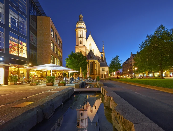 Thomaskirche Leipzig - Musikstadt Leipzig Blick auf die angestrahlte Thomaskirche in der Abend-Dämmerung, links davor das Brauhaus mit Freisitz und rechts davon die grüne Thomaswiese mit Bäumen, Kultureinrichtung, Freizeit, Musik, Bach