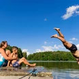 Baden im Thümmlitzsee bei Grimma Ein Mann springt kopfüber in den idyllischen Thümmlitzsee; am Ufer beobachten eine Frau und ein Kind.