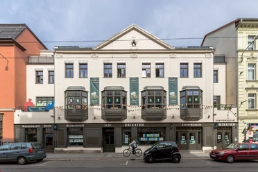 Muzeum dla dzieci UNIKATUM z kawiarnią muzealną Goetz - Muzea w Lipsku Widok z zewnątrz na muzeum dla dzieci Unikatum, napis "UNIKATUM" wielkimi literami w oknach, duże plakaty i kolorowa girlanda wiszą na fasadzie, rodzina, instytucja kultury, obiekt rekreacyjny