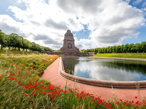 Mémorial de la bataille des Nations avec le lac des larmes devant, entouré de prairies en fleurs et d'arbres verts par beau temps, sites touristiques, musée, culture, architecture