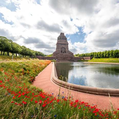 Monument to the Battle of the Nations with the Lake of Tears - Sights in Leipzig Monument to the Battle of the Nations with the Lake of Tears in front of it, surrounded by flowering meadows and green trees in good weather, sights, museum, culture, architecture