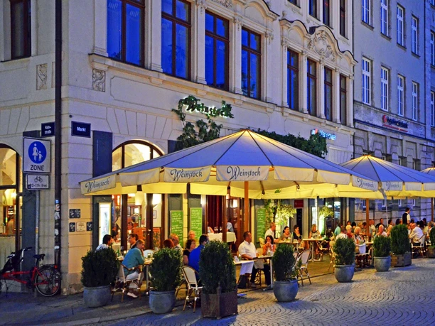 Weinstock Leipzig - Gastronomie in Leipzig Das Restaurant Weinstock am Marktplatz gegenüber vom Alten Rathaus bei der Abenddämmerung und zahlreichen Gästen im Freisitz, Gastronomie in Leipzig, Weinbar