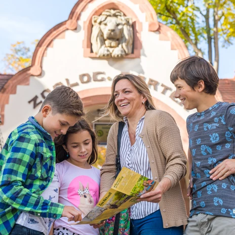Rodina stojí před vchodem do Zoo Lipsko a dívá se na skládací mapu Zoo Lipsko, rodina, s dětmi, volný čas, výlet.