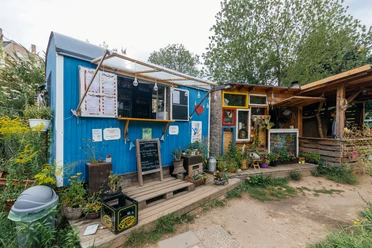Zum Wilden Heinz - Cafés in Leipzig Blick auf den blauen Ausschank-Wagen sowie den angrenzenden Holzverschlag im "Zum Wilden Heinz"-Biergarten, freisitz, gastronomie