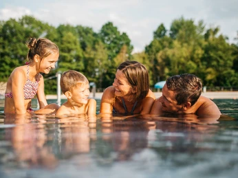 Johannisbad Außenbecken Familie genießt gemeinsames Schwimmen im Außenbecken des Johannisbades an einem sonnigen Tag.Family enjoying a swim together in the outdoor pool at Johannisbad on a sunny day.Rodina si za slunečného dne užívá společné koupání ve venkovním bazénu v lázních Johannisbad.Rodzina pływająca razem w odkrytym basenie w Johannisbad w słoneczny dzień.Familie geniet samen van een duik in het buitenzwembad van het Johannisbad op een zonnige dag.Famiglia che si gode una nuotata insieme nella piscina all'aperto del Johannisbad in una giornata di sole.