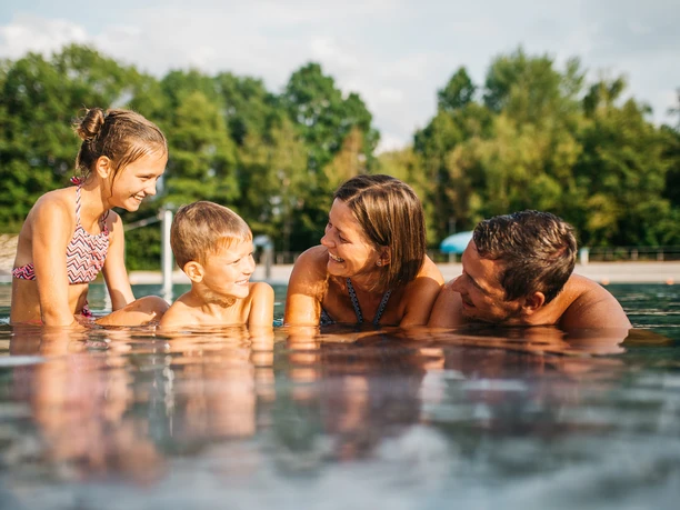 Johannisbad Außenbecken Familie genießt gemeinsames Schwimmen im Außenbecken des Johannisbades an einem sonnigen Tag.