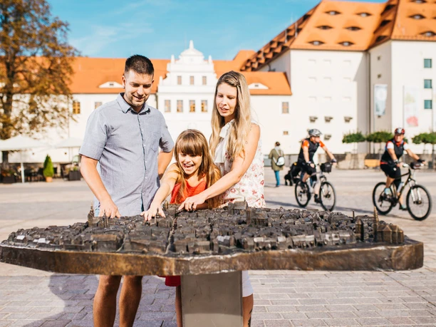 Familie vor Schloss Freudenstein_Foto_Paul Schmidt.jpg Eine Familie erkundet ein Bronze-Stadtmodell vor Schloss Freudenstein.