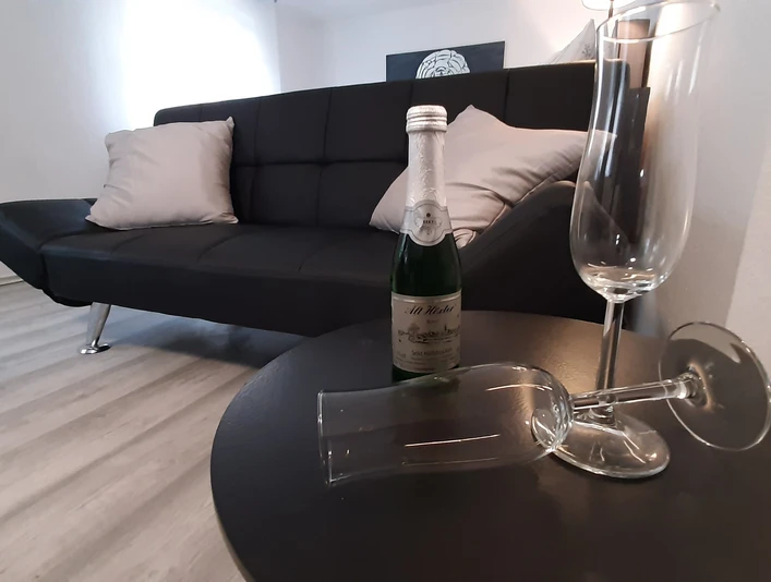 Sofa mit Beistelltischchen und SektgläsernSofa with side table and champagne glasses
