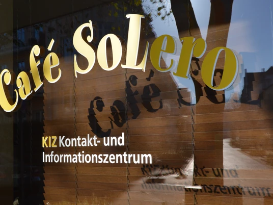 KIZ Café SoLero Bad Oeynhausen.JPG Auf dem Bild sind die Schaufenster des Cafés zu sehen, wobei der goldene Schriftzug „Café SoLero“ im Vordergrund besonders hervorsticht.