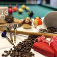 KIZ Café SoLero Bad Oeynhausen 2.jpg Auf dem Bild sind Billiardkugeln zu sehen, daneben liegen Dartscheiben, die an einem Billardstock angelehnt sind, sowie Kaffeebohnen.