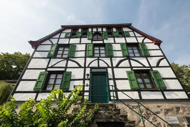 Altes Doktorhaus in Haan-Gruiten Fachwerkhaus mit grünen Fensterläden, historische Architektur, vor klar blauem Himmel.