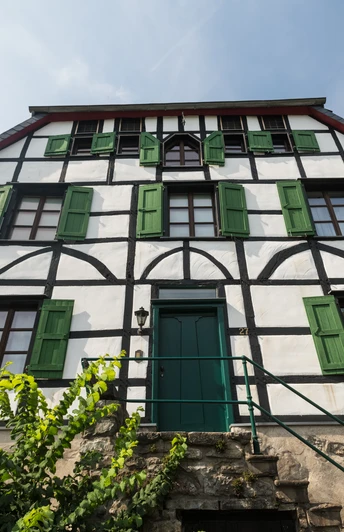 Altes Doktorhaus in Haan-Gruiten Fachwerkhaus mit grünen Fensterläden, historische Architektur, vor klar blauem Himmel.