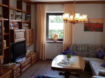 Wohnzimmer mit Einbauwand aus Holz, eleganter Hängelampe mit Glasschirmen und gemütlichem Ecksofa.