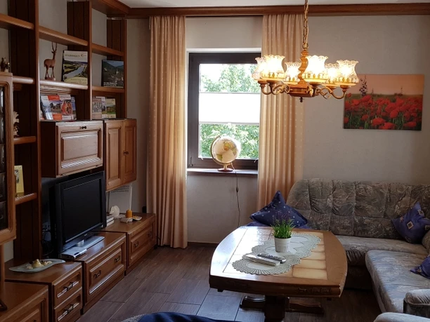 Wohnzimmer mit Einbauwand aus Holz, eleganter Hängelampe mit Glasschirmen und gemütlichem Ecksofa.