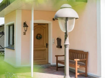 Hausansicht Eingangsbereich des Hauses mit Holztür und Holzbank davor.