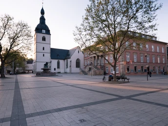 Teutoburger_Wald_Detmold_B.Fromberger_Marktplatz_CCBYSA (25).jpg Historischer Marktplatz in Detmold mit der evangelischen Kirche und Umrissen eines Brunnens bei Sonnenuntergang.