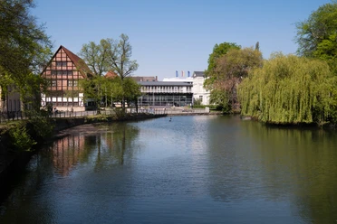 Blick auf das Lippische Landesmuseum Eine ruhige Flusslandschaft mit reflektierendem Wasser; im Hintergrund das Lippische Landesmuseum.