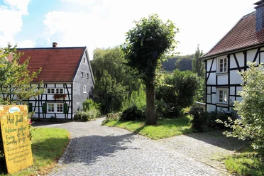 Einladender Hofladen auf dem Biohof Judt im Windrather Tal Ein Hofladen umgeben von Fachwerkhäusern und grünen Bäumen lädt im Windrather Tal zum Einkauf ein.