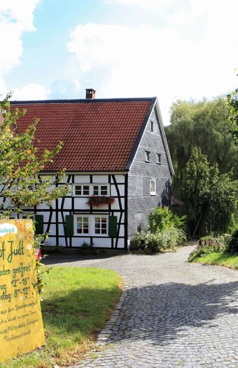 Einladender Hofladen auf dem Biohof Judt im Windrather Tal Ein Hofladen umgeben von Fachwerkhäusern und grünen Bäumen lädt im Windrather Tal zum Einkauf ein.