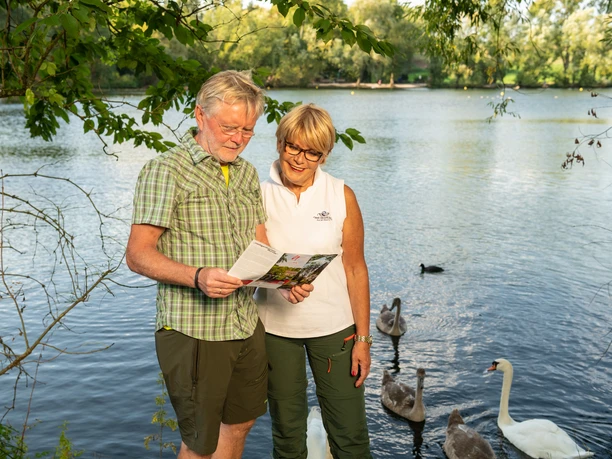 Entlang des Abtskücher Teiches in Heiligenhaus Ein älteres Paar steht am Ufer des Abtskücher Teiches und betrachtet aufmerksam ein Faltblatt.