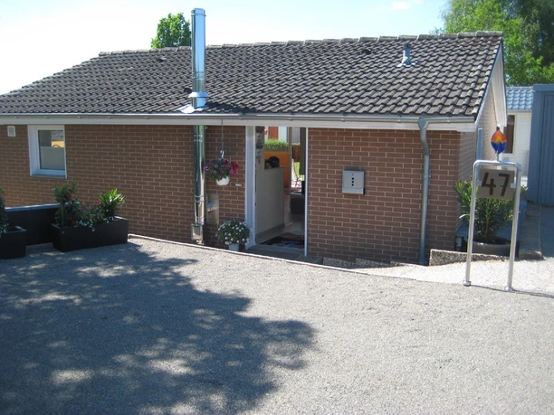 Einstöckiges Ziegelgebäude mit Flachdach, Hausnummer 47, Eingang links, Parkplatz im Vordergrund.