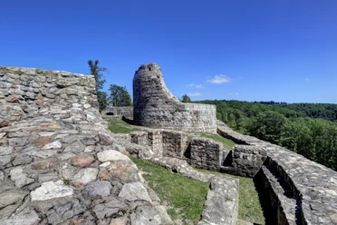 Mittelalterliche Burgruine Falkenburg auf einem Hügel, umgeben von grünen Wäldern und blauem Himmel.