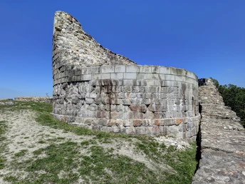 Ruinen der Falkenburg in Detmold, umgeben von grüner Landschaft und strahlend blauem Himmel.