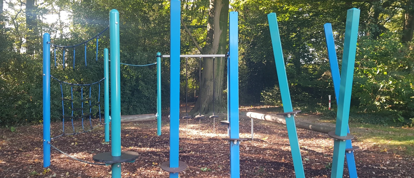 Bürgerpark-Schapen_Spielbereich_©SG-Spelle.jpg Modern gestalteter Spielbereich mit blauen Kletterelementen im schattigen Bürgerpark Schapen.