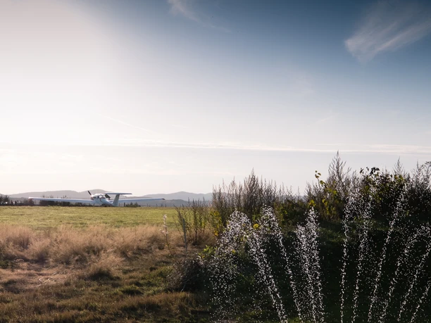 Flugplatz Detmold Früher Morgen am Flugplatz Detmold mit einer kleinen Maschine vor malerischen Hügeln im Hintergrund.