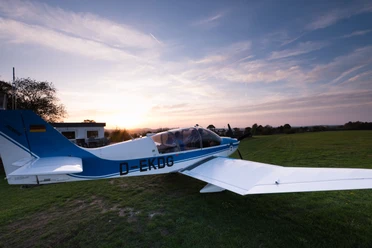 Flugplatz Detmold Ein kleines Flugzeug steht auf einer Grasfläche am Flugplatz Detmold, umgeben von Abendsonne.