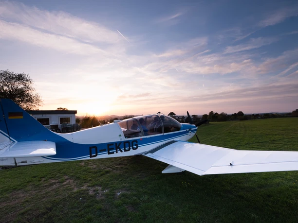 Flugplatz Detmold Ein kleines Flugzeug steht auf einer Grasfläche am Flugplatz Detmold, umgeben von Abendsonne.