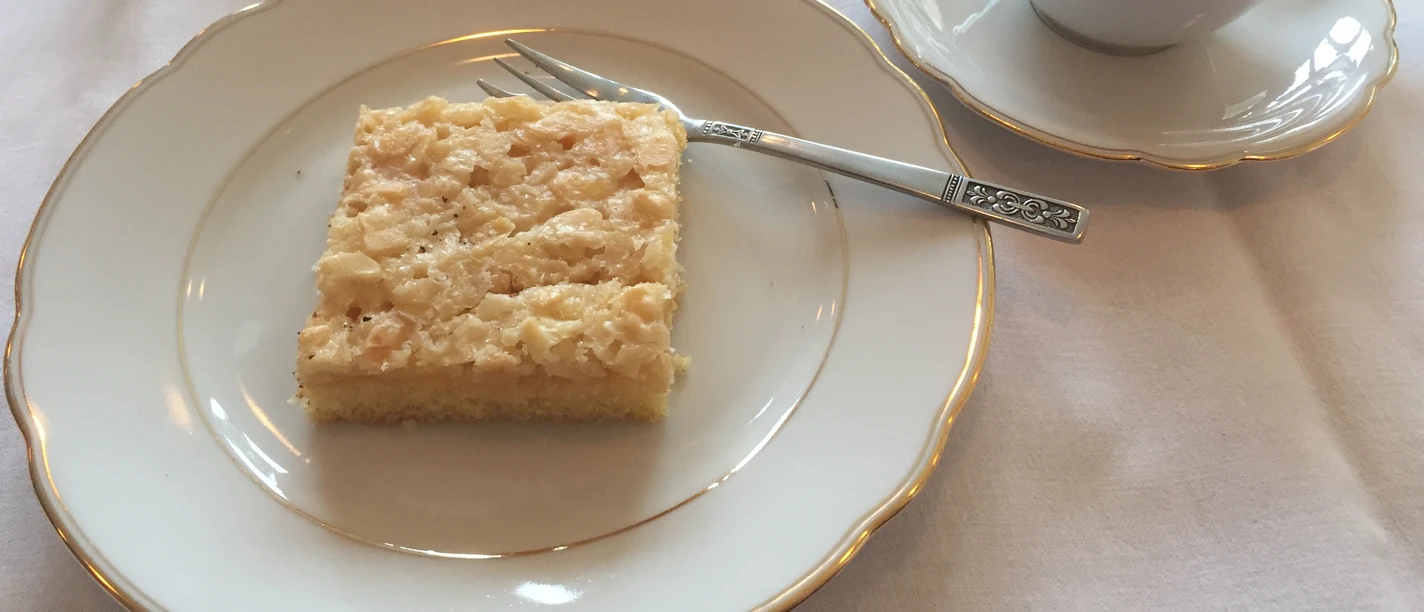 A laid table with a cup of coffee and a slice of apple pie on a white plate.