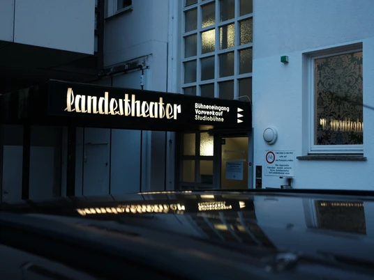 Theaterkasse Eingang des Landestheaters mit beleuchtetem Schild und gläsernem Treppenaufgang am Abend.