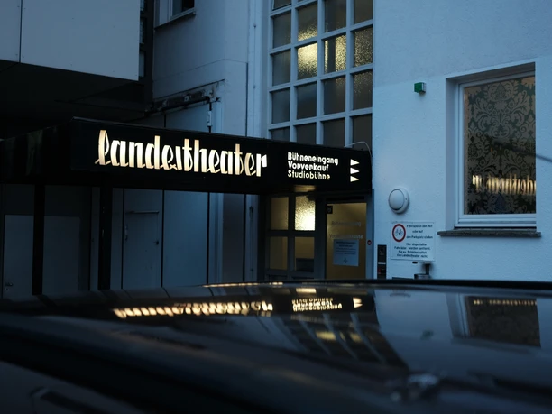Theaterkasse Eingang des Landestheaters mit beleuchtetem Schild und gläsernem Treppenaufgang am Abend.