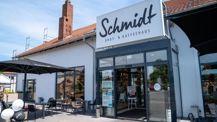 Dies ist die Außenansicht der Bäckerei Schmidt mit Sitzgelegenheiten..